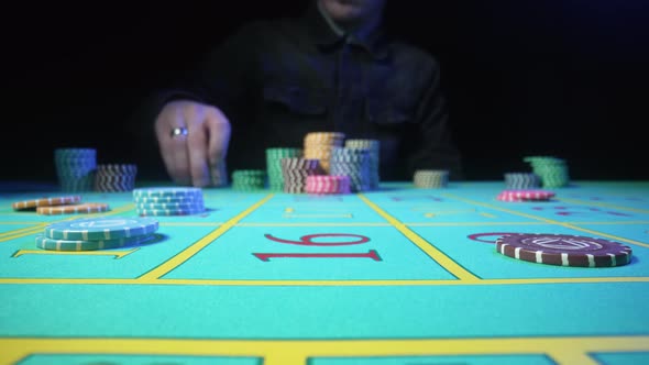 Unrecognizable Male Gambler Makes Bets While Sitting at a Roulette Table in a Casino