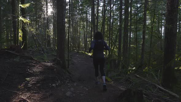 Caucasian Woman Trail Running in the Green Forest