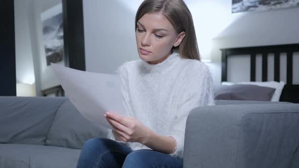 Young Woman Reading Letter While Sitting on Sofa