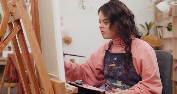 Pretty Girl with Down Syndrome Painting and Singing in Her Room, Concentrated Chid Wearing Aprone