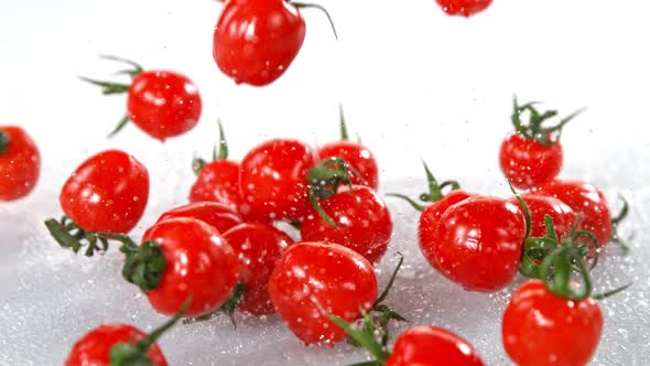 Super Slow Motion Shot of Cherry Tomatoes Falling Into Water on White Background at 1000Fps