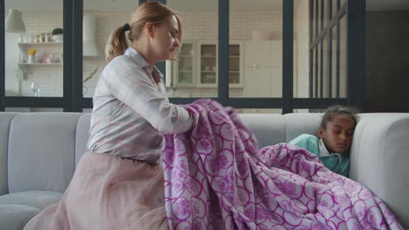 Caring Mother Covering Sick Daughter with Blanket