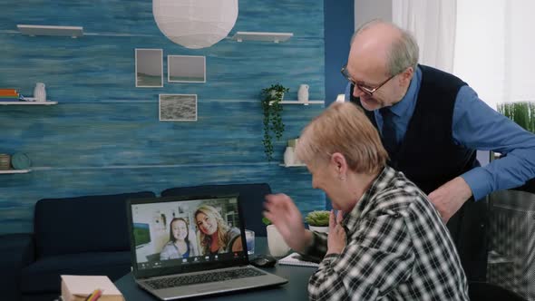 Happy Senior Couple Grandparents Waving at Laptop Computer During Video Call