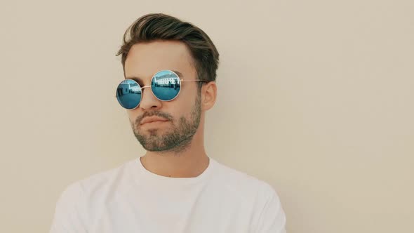 Portrait of handsome stylish hipster man posing outdoors at summer sunny day