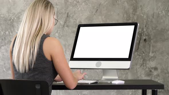 Businesswoman Sitting at Her Desk in the Office Working on a Desktop Monitor. White Display.