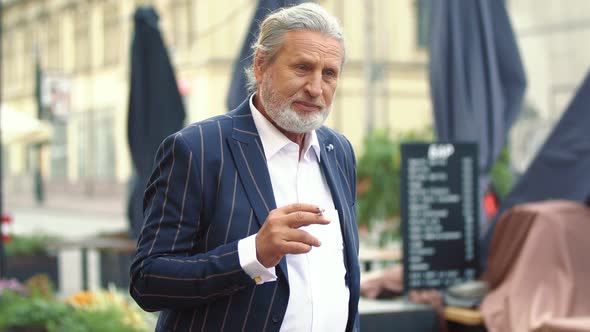 an Elderly Man Smokes a Cigarette