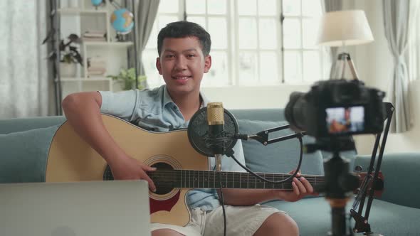 Asian Boy Is A Vlogger With Guitar Smiling To Camera. The Boy Is Streaming