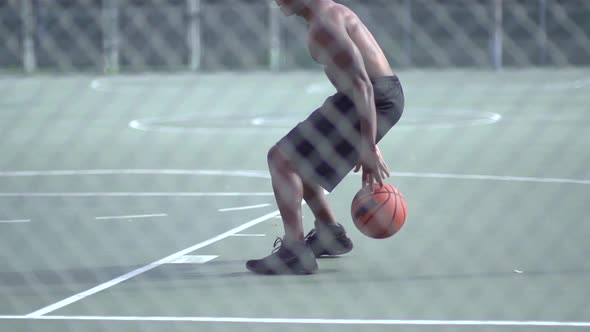 A young man playing basketball on a rainy day.