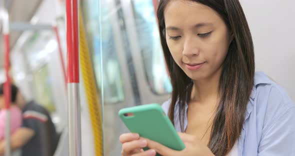 Woman working on mobile phone in train station 