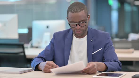 African Businessman Celebrating Success While Reading Documents
