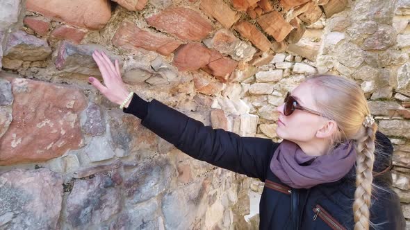 Tourist Looks at a Stone Wall in Ancient Castle.