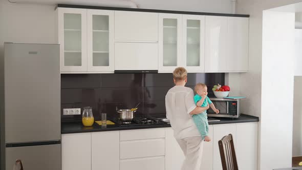 Woman with Toddler on Hands Cooking on Kitchen