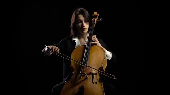 Woman Plays the Cello on Dark Studio. Black Background
