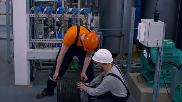 Two Workers in Helmets at a Chemical Plant Do Their Job