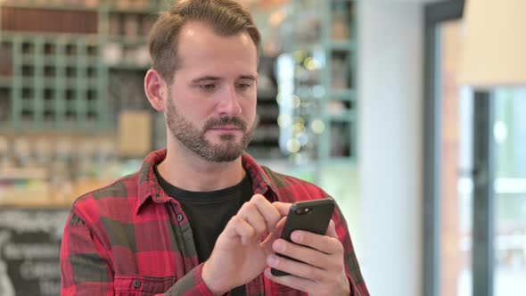 Portrait of Smartphone Use By Serious Young Man 