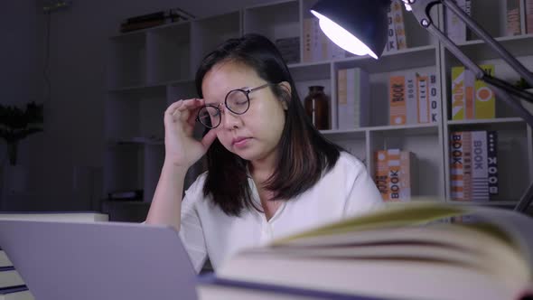 Stressed asian woman working on laptop at night at home
