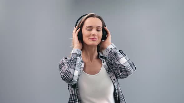 Pleasant Young Blonde Woman Wearing Headphones Enjoying Audio Sound Dancing Isolated on Gray