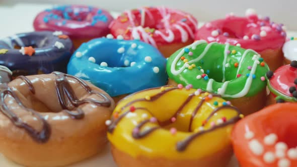 Lush Round Pastries Donuts with Multicolored Glaze Lie on a White Table Covered with Whitedark