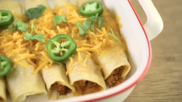 Chicken enchiladas with cheddar cheese and sauce.