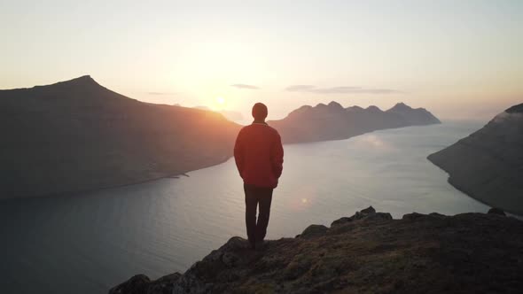 Hiker On Mountain Watching Sun Rise Over Klakkur