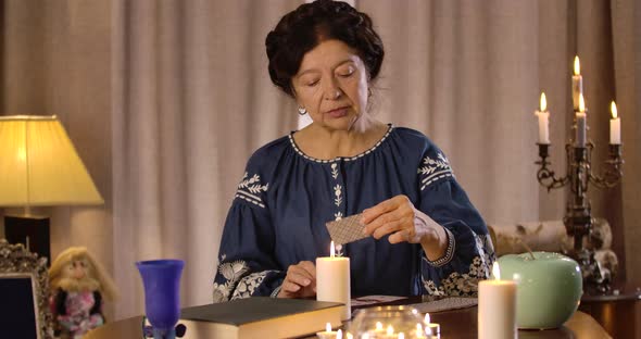 Old Caucasian Female Fortune Teller Taking Out Cards and Showing Ace of Spades To Camera. Worried