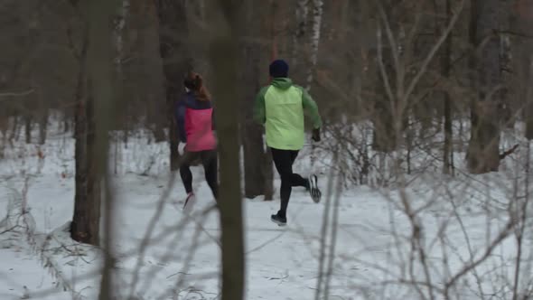 Athletes Couple Running Through Winter Woodland