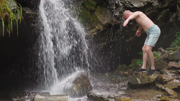 Tourist Wets Bald Head with Waterfall Streams at Highland