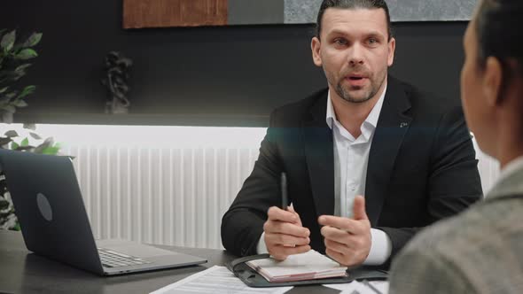 Male Salesman Gives a Consultation to Women in Modern Grey Office Room