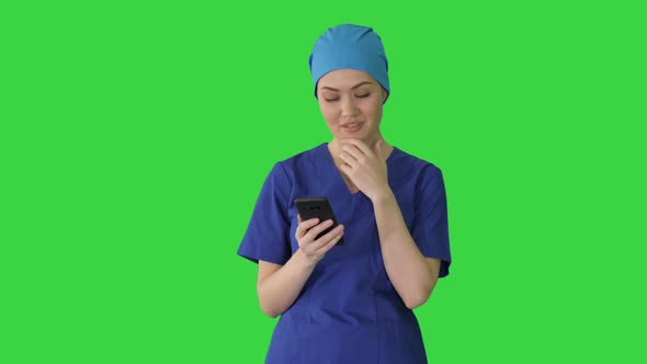 Thinking Female Doctor Using Her Smartphone on a Green Screen, Chroma Key.