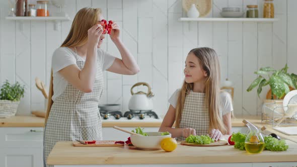 Funny Cheerful Mother Mature Woman Cooking with Teenage Daughter Girl Cutting Lettuce Salad Prepare