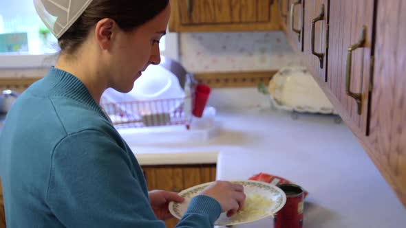 A Mennonite woman adds cheese to a homemade dish in slow motion.