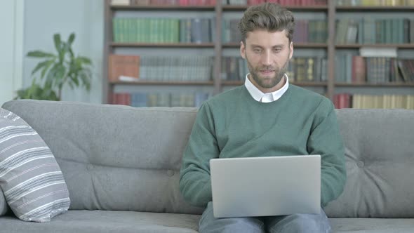 Successful Man Working on Laptop and Celebrating While Sitting on Sofa