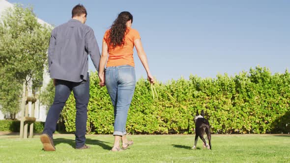 Happy caucasian couple is taking their dog for a walk