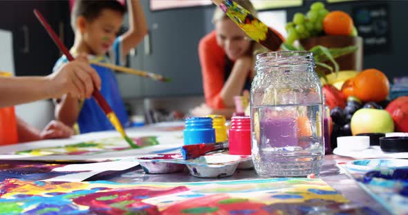 Teacher assisting schoolkid in drawing class