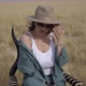 Young Woman in Hat Sits on Chair and Poses in the Savannah on a Dry Grass Field - VideoHive Item for Sale