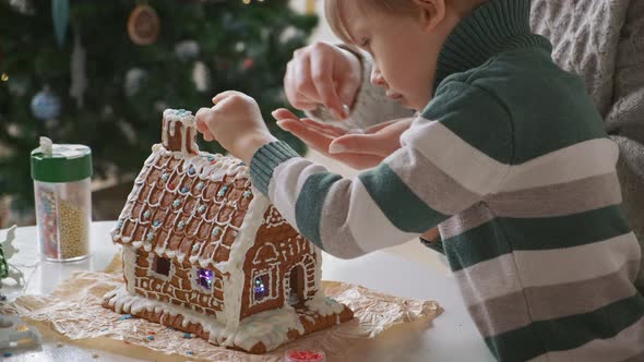 Little Boy with Mother Decorating Christmas Gingerbread House Together Family Activities and