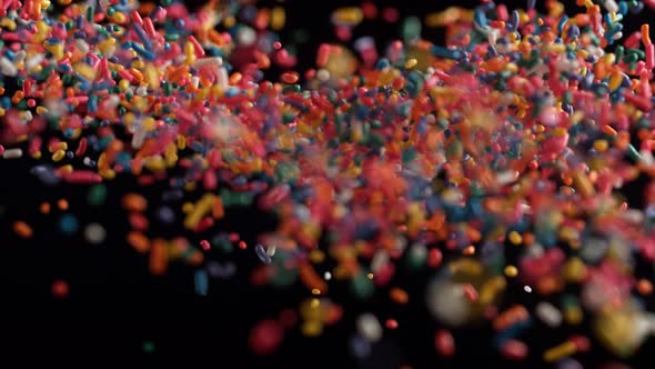 Camera follows rainbow chocolate sprinkles frying in the air. Slow Motion.