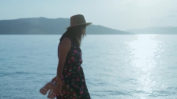 A Carnivorous Girl in a Hat and Dress Walks on the Seashore