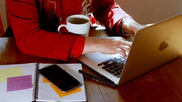 Mature woman using laptop in kitchen at home 4k