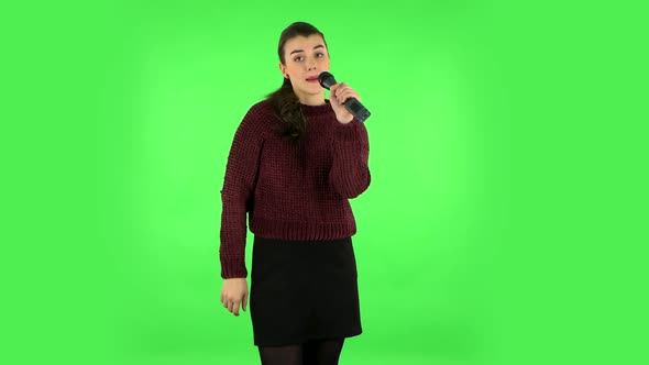 Attractive Girl Sings Into a Microphone and Moves To the Beat of Music. Green Screen