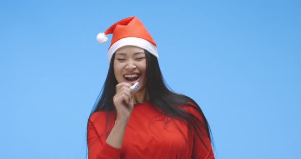Young Woman Partying in Santa Hat with Party Horn