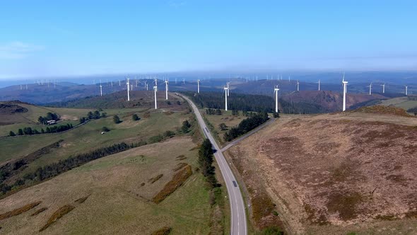 Large wind turbine park in operation and a two-way road that crosses through the middle of the windm
