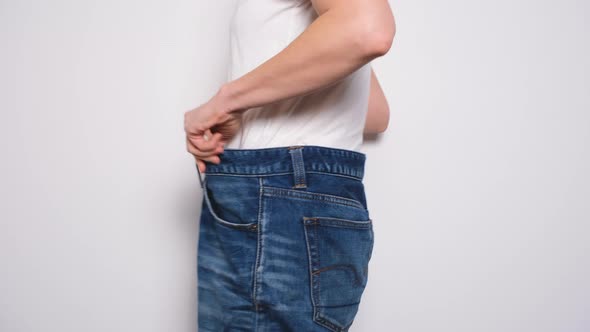 Happy Woman Dancing in Oversized Jeans on White Background