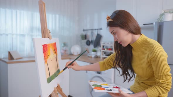 Asian young talented woman artist coloring on painting board in house.