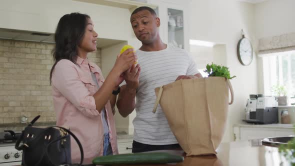 Happy biracial couple unpacking groceries in kitchen