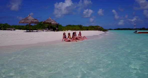 Modern happy ladies relaxing spending quality time at the beach on sunny blue and white sand backgro