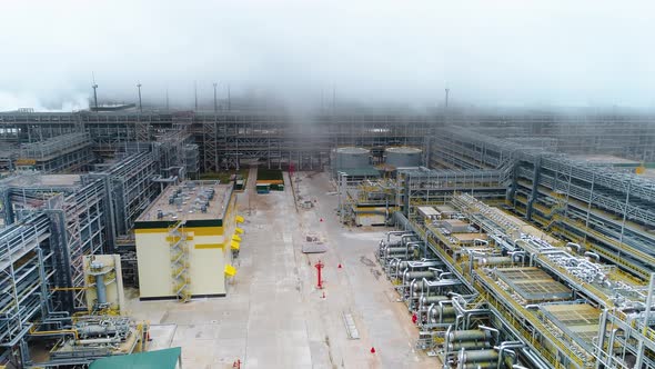 High-tech gasoline and fuel plant with pipelines on foggy day. Drone footage.