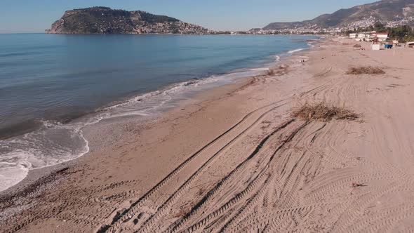 Seashore of Alanya city after heavy storm. Dirt polluted beach with tree debris and plastic garbage