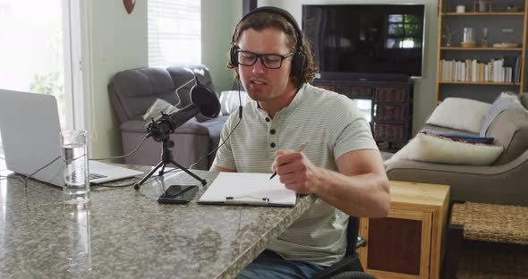 Focused caucasian man working remotely, using laptop and headphones