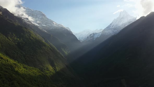 Epic rotating aerial shot of the sun shining through the mountain onto a mountain face inside the An